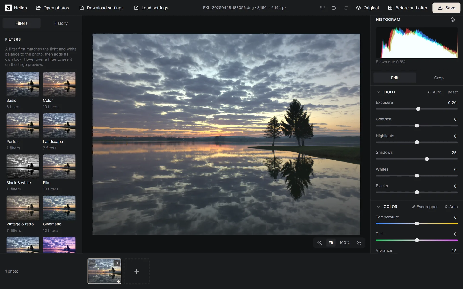 The Helios editor showing an open photo of a sunset over a lake, with the filter categories on the left and the histogram and light and colour sliders on the right.