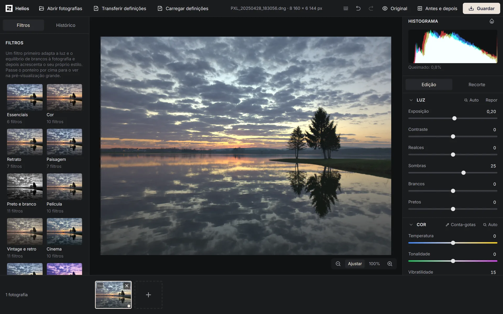 O editor Helios mostra uma fotografia aberta de um pôr do sol sobre um lago, com as categorias de filtros à esquerda e, à direita, o histograma e os controlos de luz e cor.