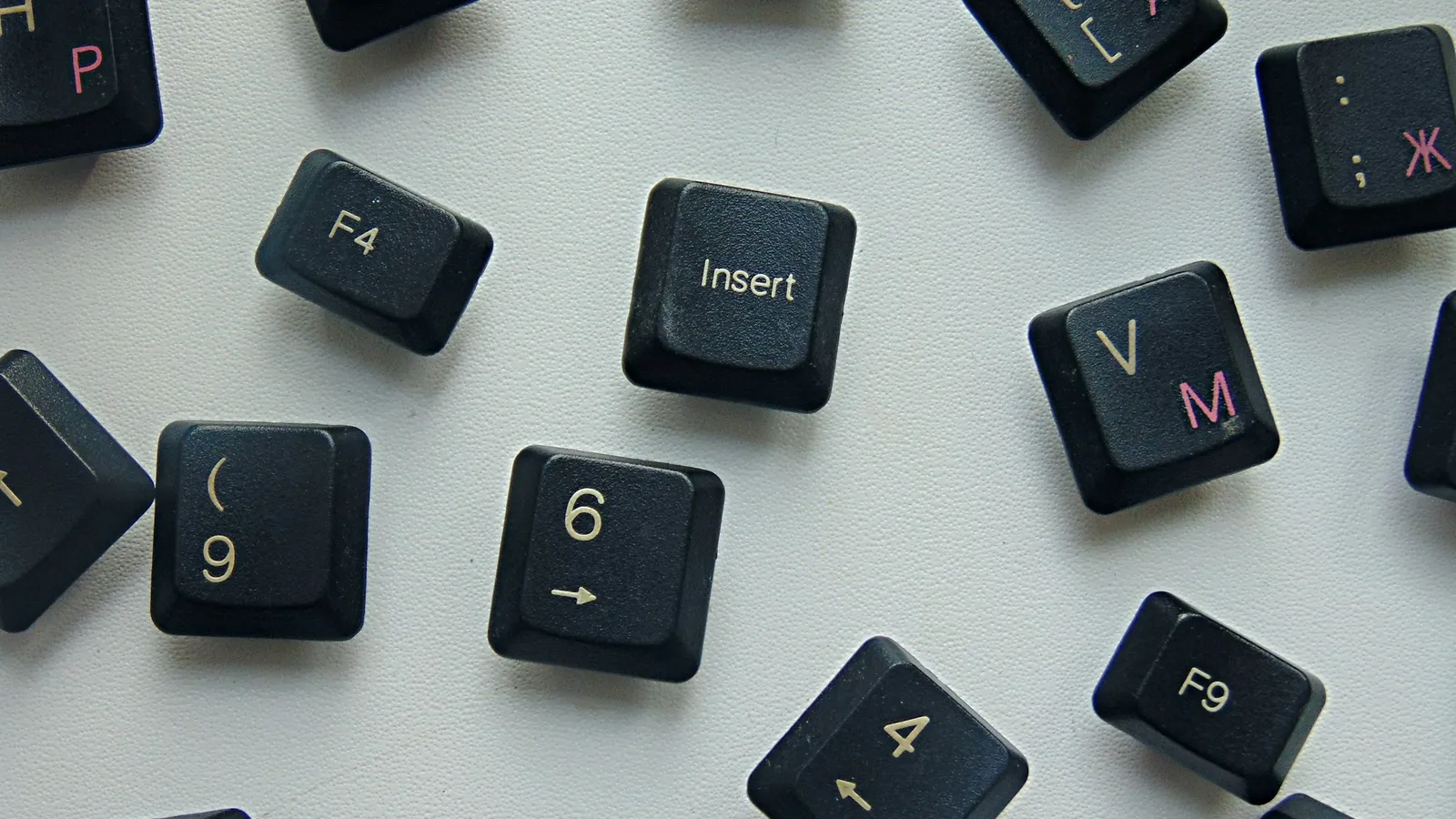 Rozsypane czarne klawisze klawiatury z łacińską literą V, rosyjskimi literami М i Ж oraz klawiszami Insert, F4 i F9