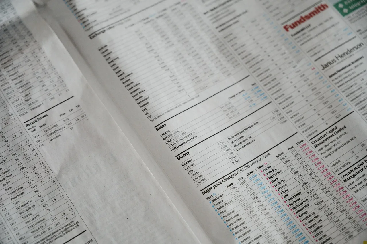 An open newspaper with share price tables, columns labelled by headings