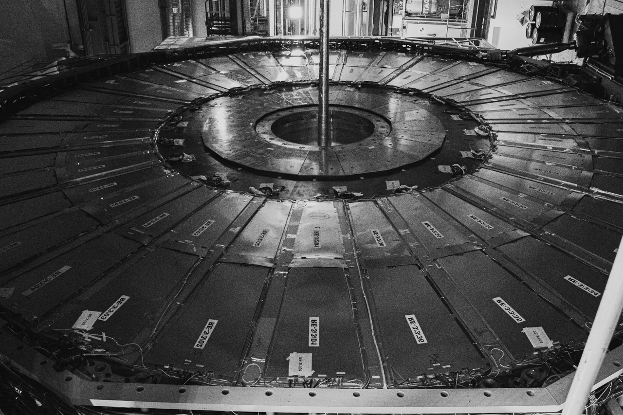 Czarno-biała fotografia okrągłej części detektora CMS w CERN złożonej z ponumerowanych segmentów z oznaczeniami RE