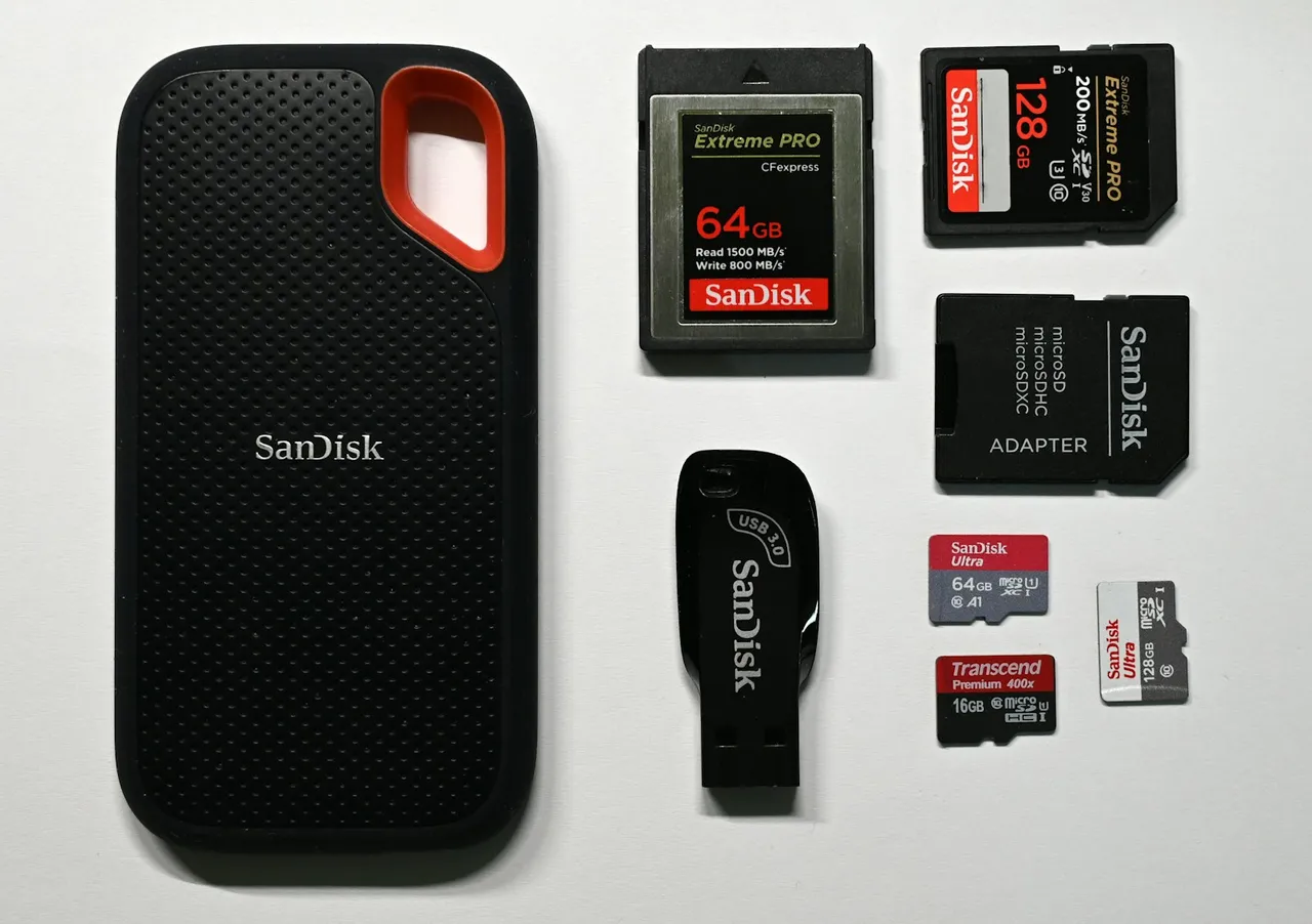 SSD portátil SanDisk, memoria USB 3.0 SanDisk, tarjeta CFexpress de 64GB, tarjeta SD de 128GB, adaptador microSD y tres tarjetas microSD de 16GB, 64GB y 128GB sobre fondo blanco