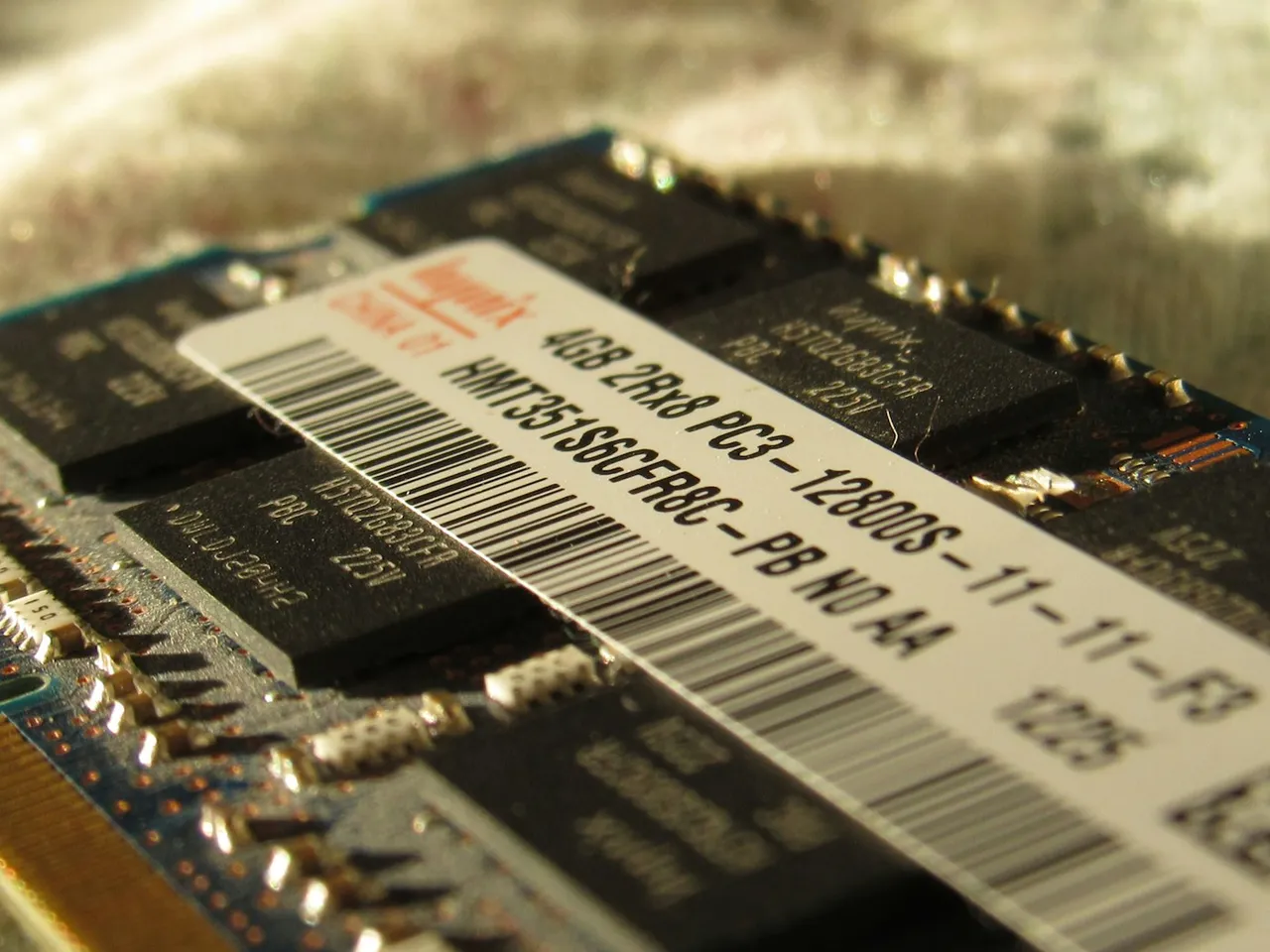 Moduł pamięci RAM z naklejką z napisem 4GB 2Rx8 PC3-12800S-11-11-F3, obok naklejki czarne kości z oznaczeniem H5TQ2G83CFR