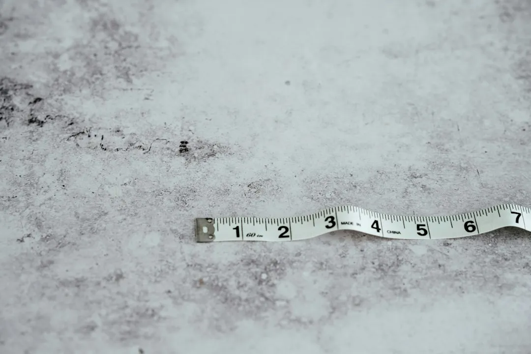 Biała taśma krawiecka na szarym blacie z cyframi od 1 do 7 i nadrukiem 60 in obok podziałki 1