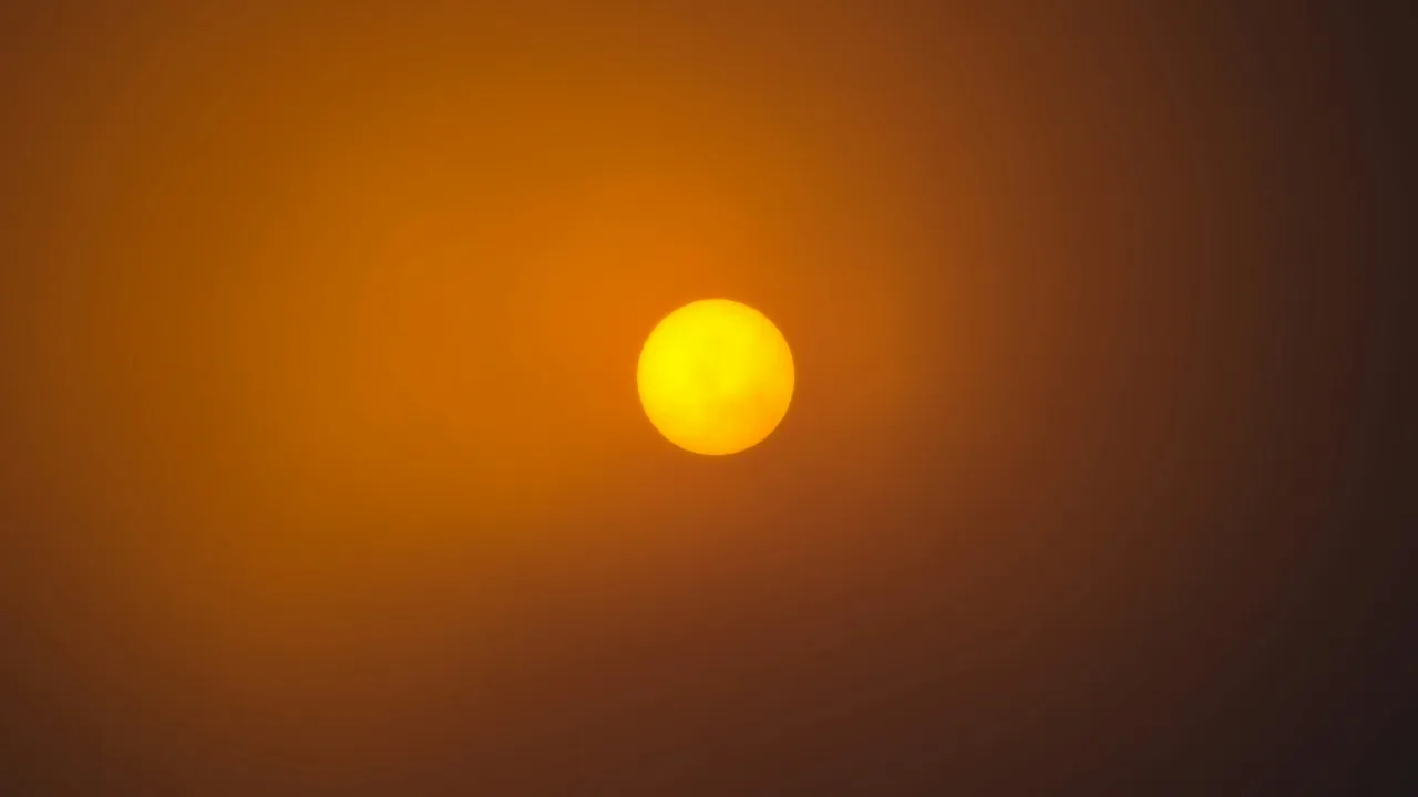 Żółta tarcza Słońca na pomarańczowym tle