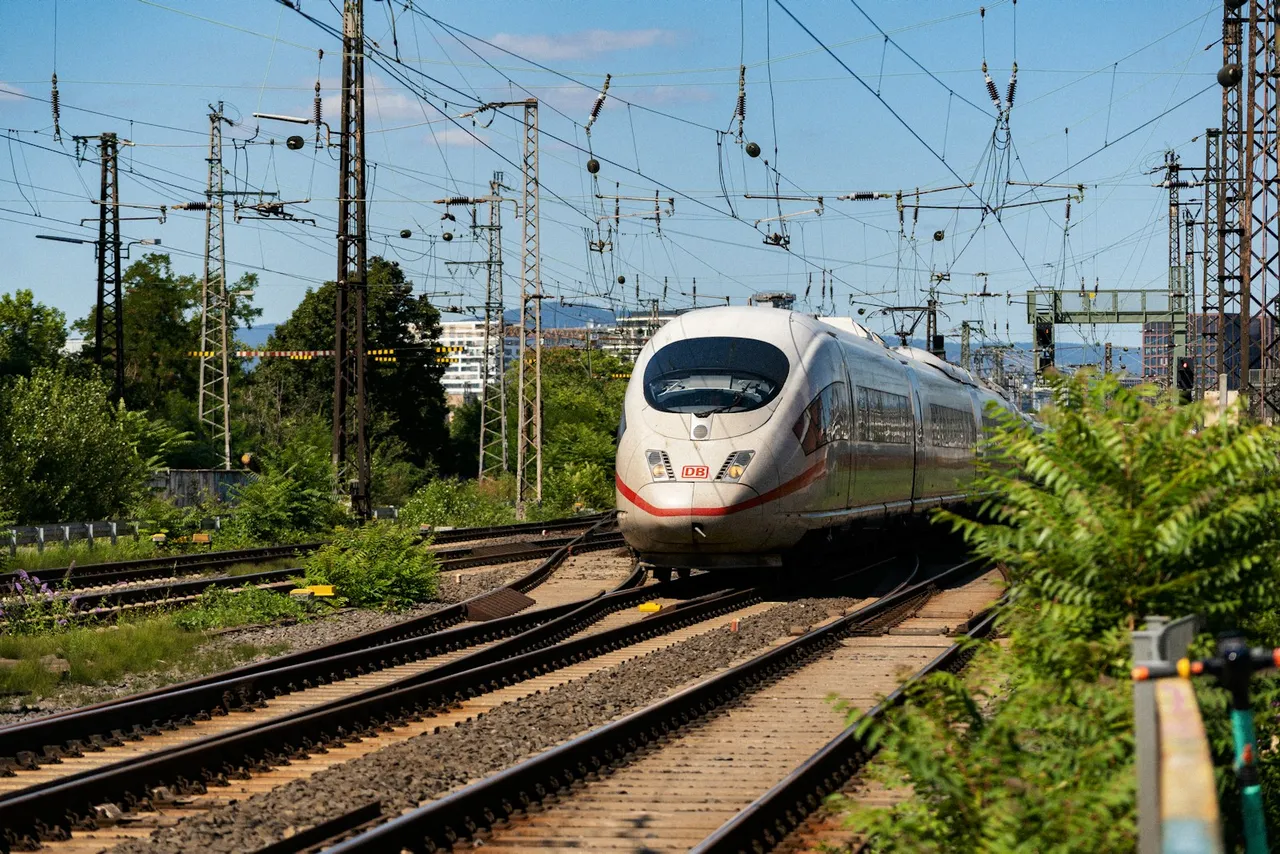 Biały pociąg dużych prędkości ICE z czerwonym pasem na torach pod siecią trakcyjną