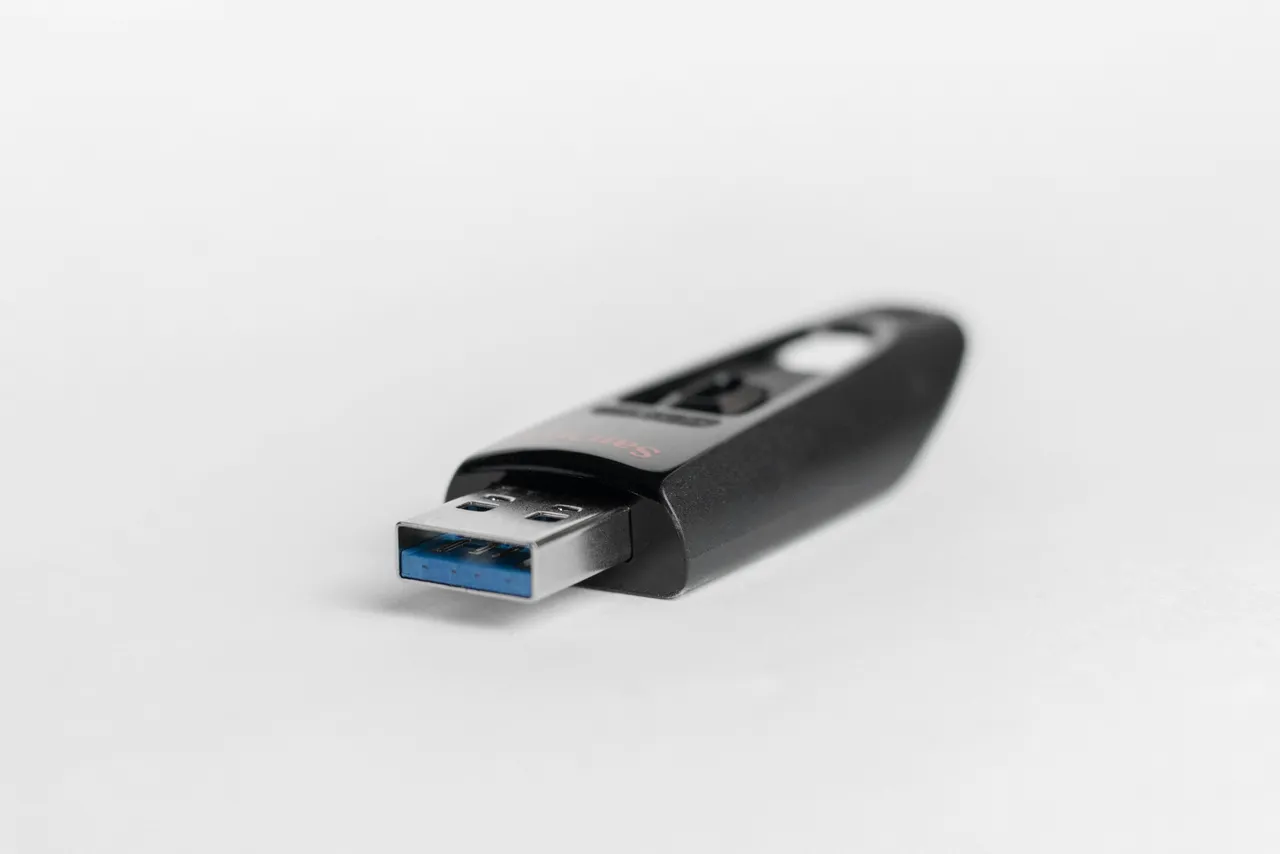 Black SanDisk flash drive with a USB-A plug on a white background