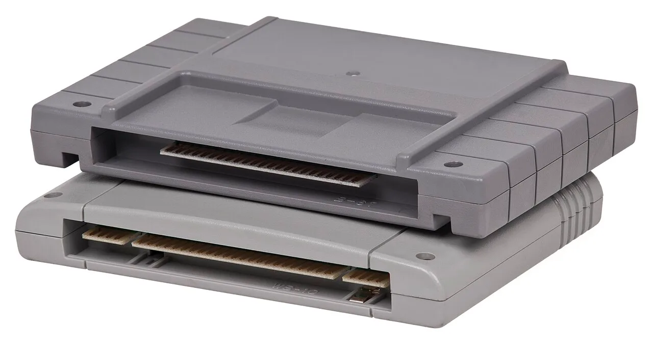 Dwa szare kartridże konsoli Super Nintendo ułożone jeden na drugim, z widocznymi złączami krawędziowymi