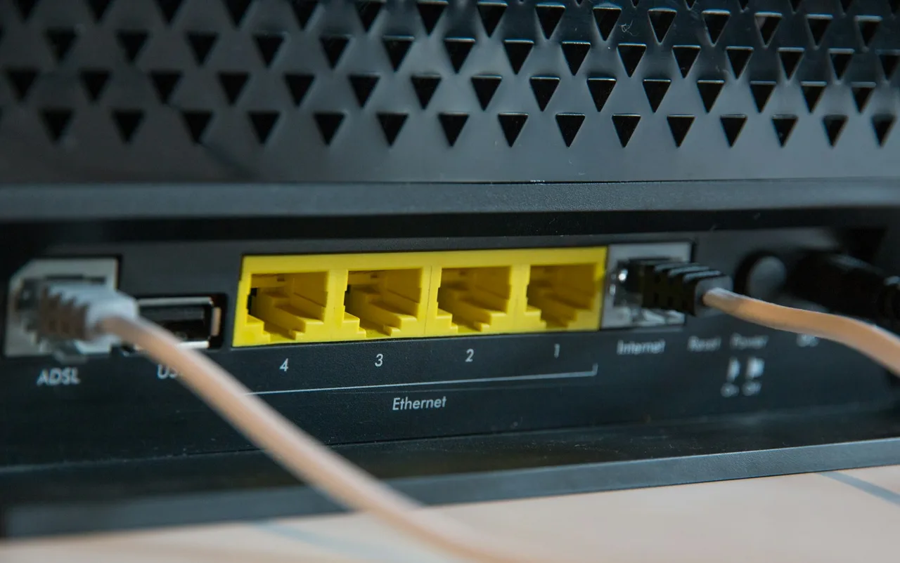 Tył domowego routera z czterema żółtymi gniazdami Ethernet ponumerowanymi od 4 do 1, obok gniazda ADSL, USB i Internet