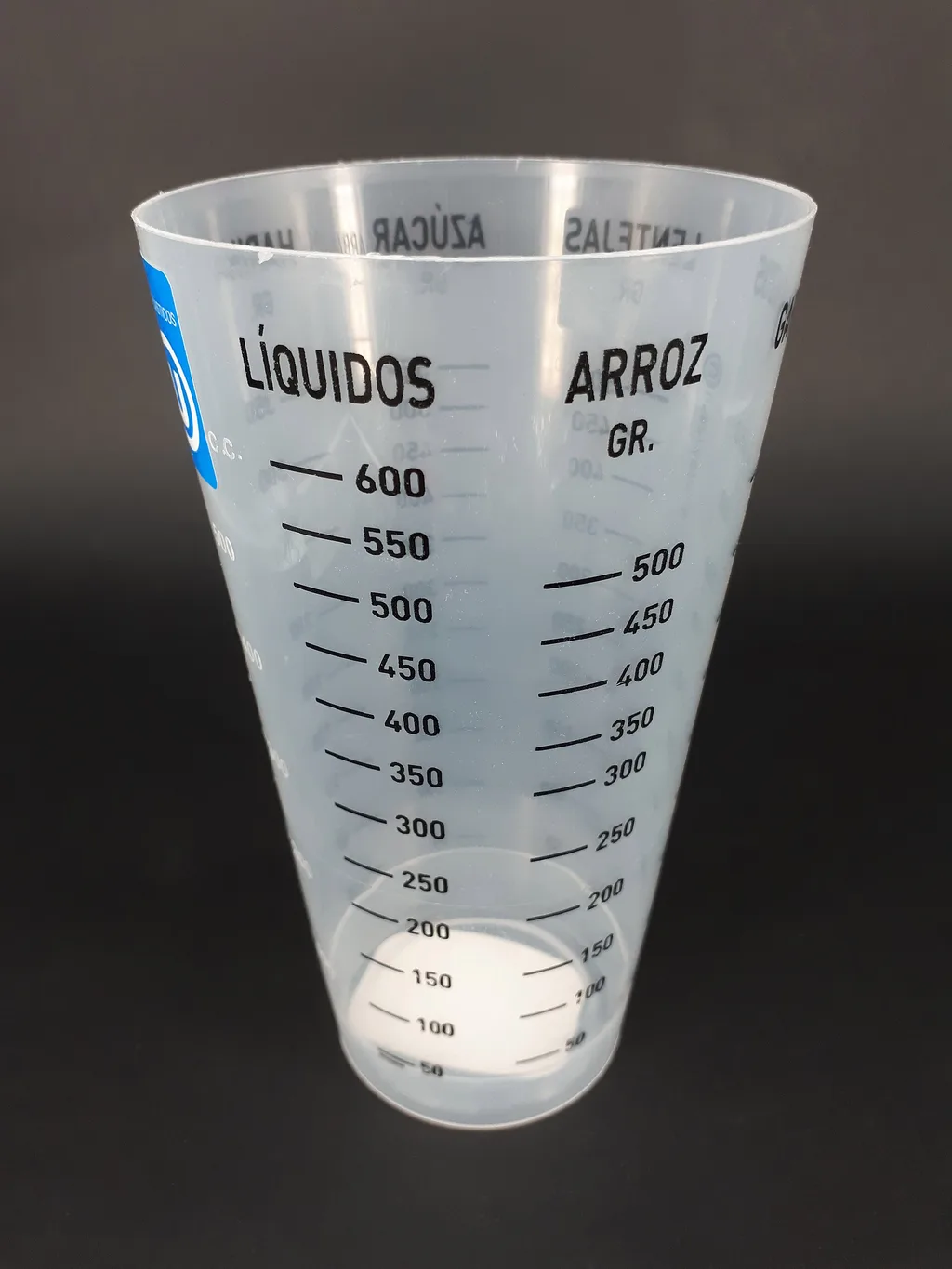 Misurino di plastica con due scale: millilitri per i liquidi e grammi per il riso