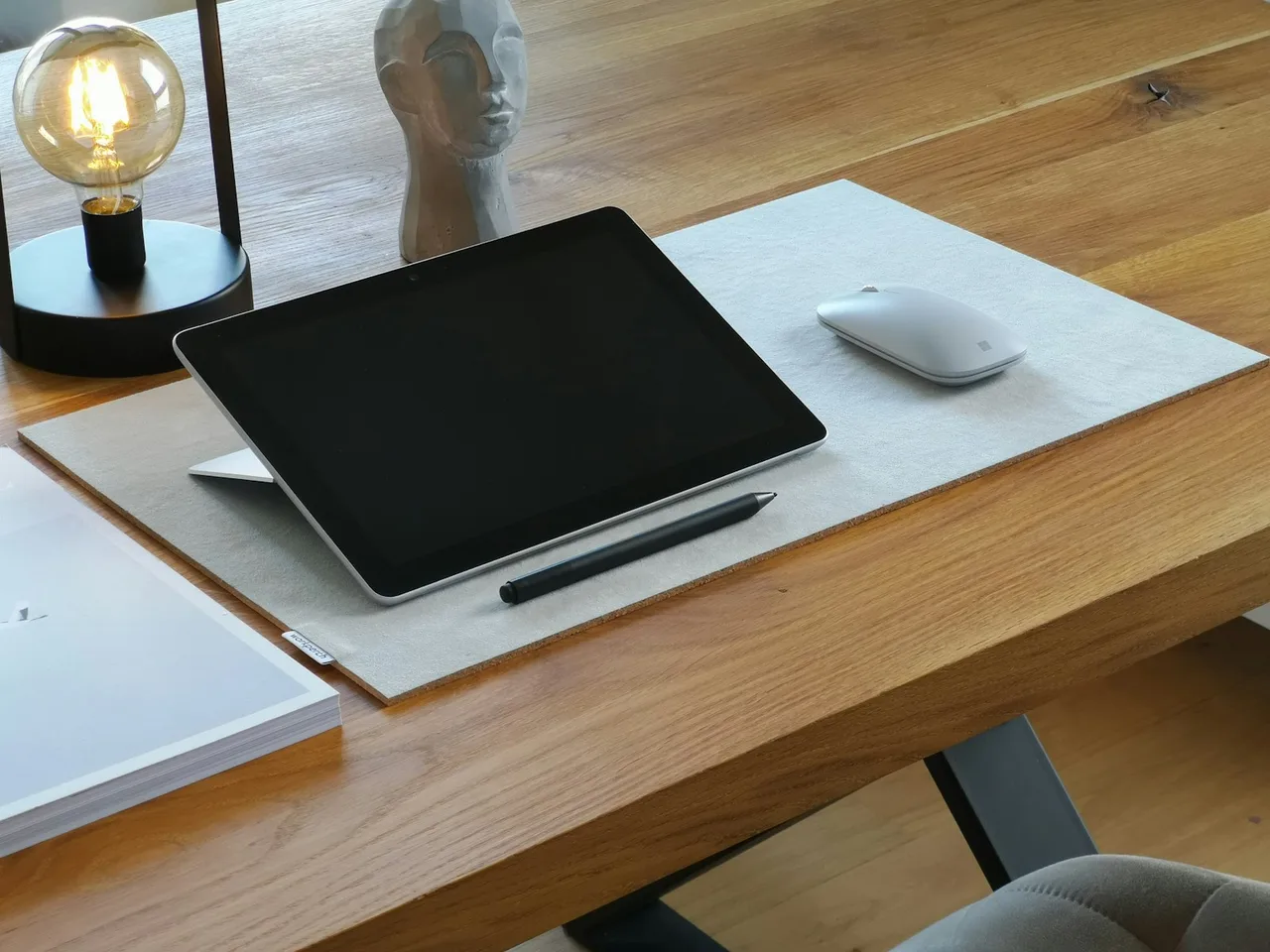 Mesa digitalizadora com caneta e rato sobre um tapete de secretária