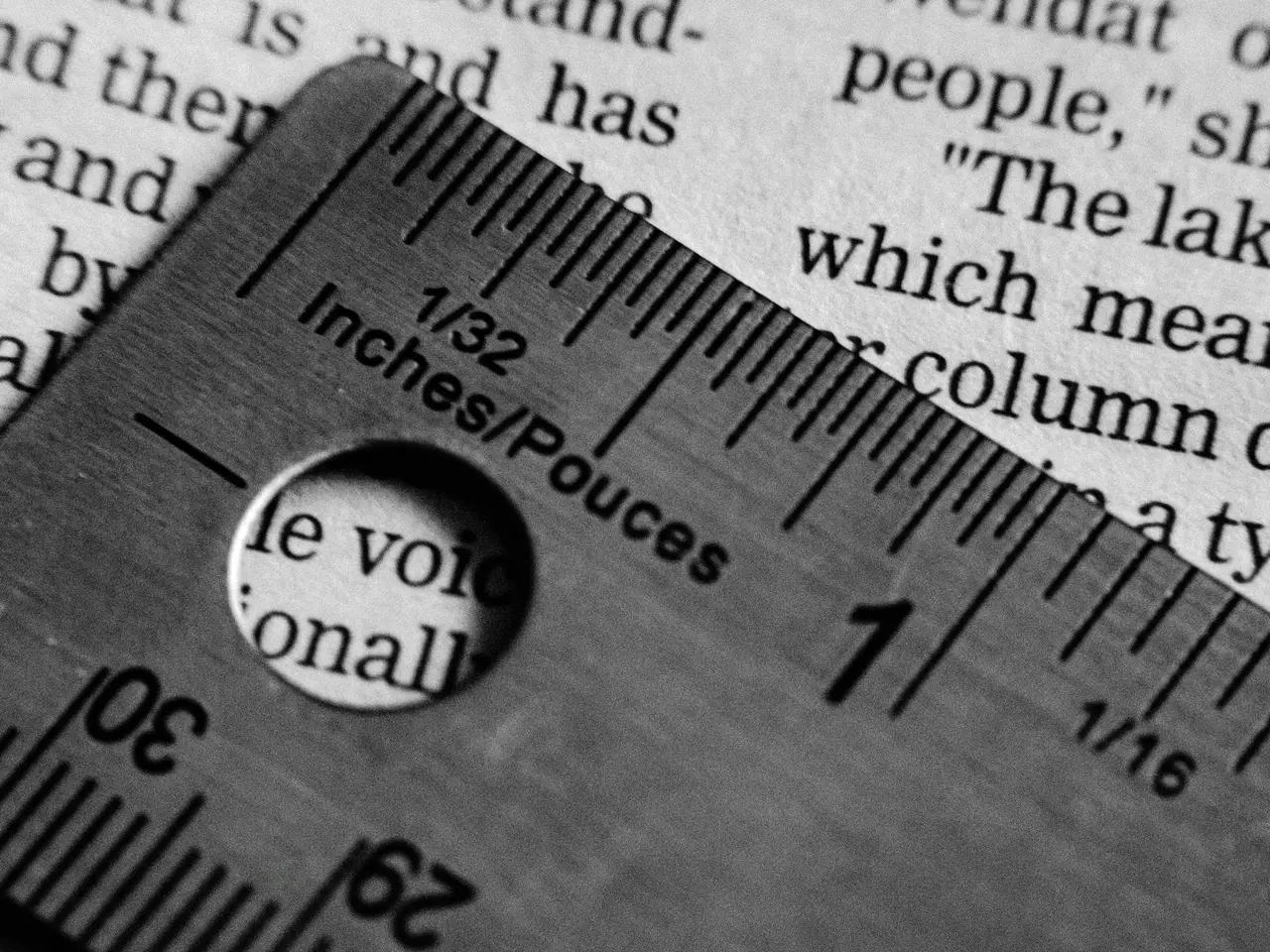 Righello d’acciaio con scale in pollici e in centimetri appoggiato su una pagina stampata