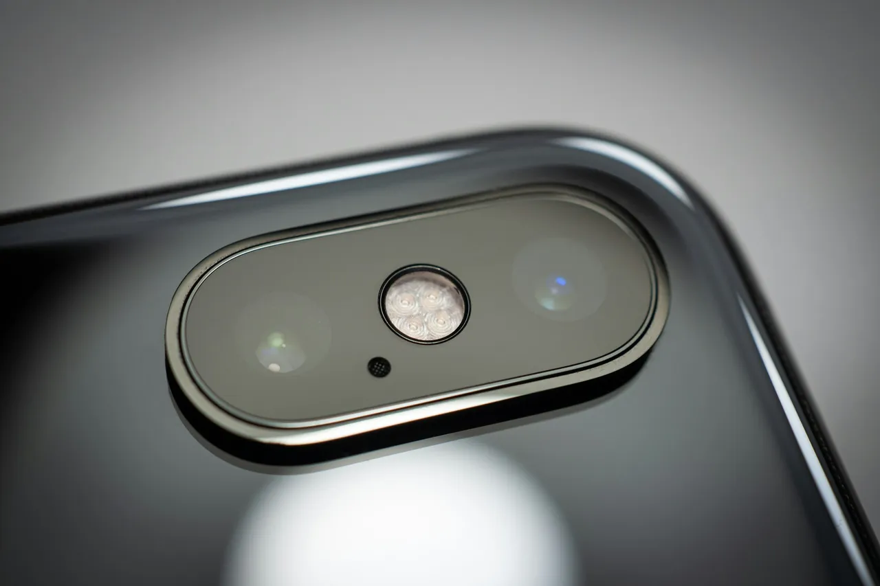 Zbliżenie tylnego aparatu iPhone’a X z dwoma obiektywami i lampą błyskową