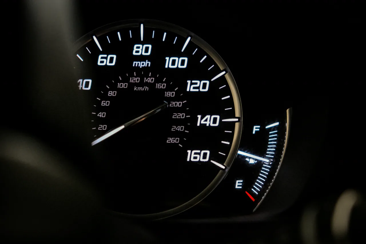 Podświetlony prędkościomierz samochodu z zewnętrzną skalą w milach na godzinę do 160 mph i wewnętrzną skalą w kilometrach na godzinę do 260 km/h
