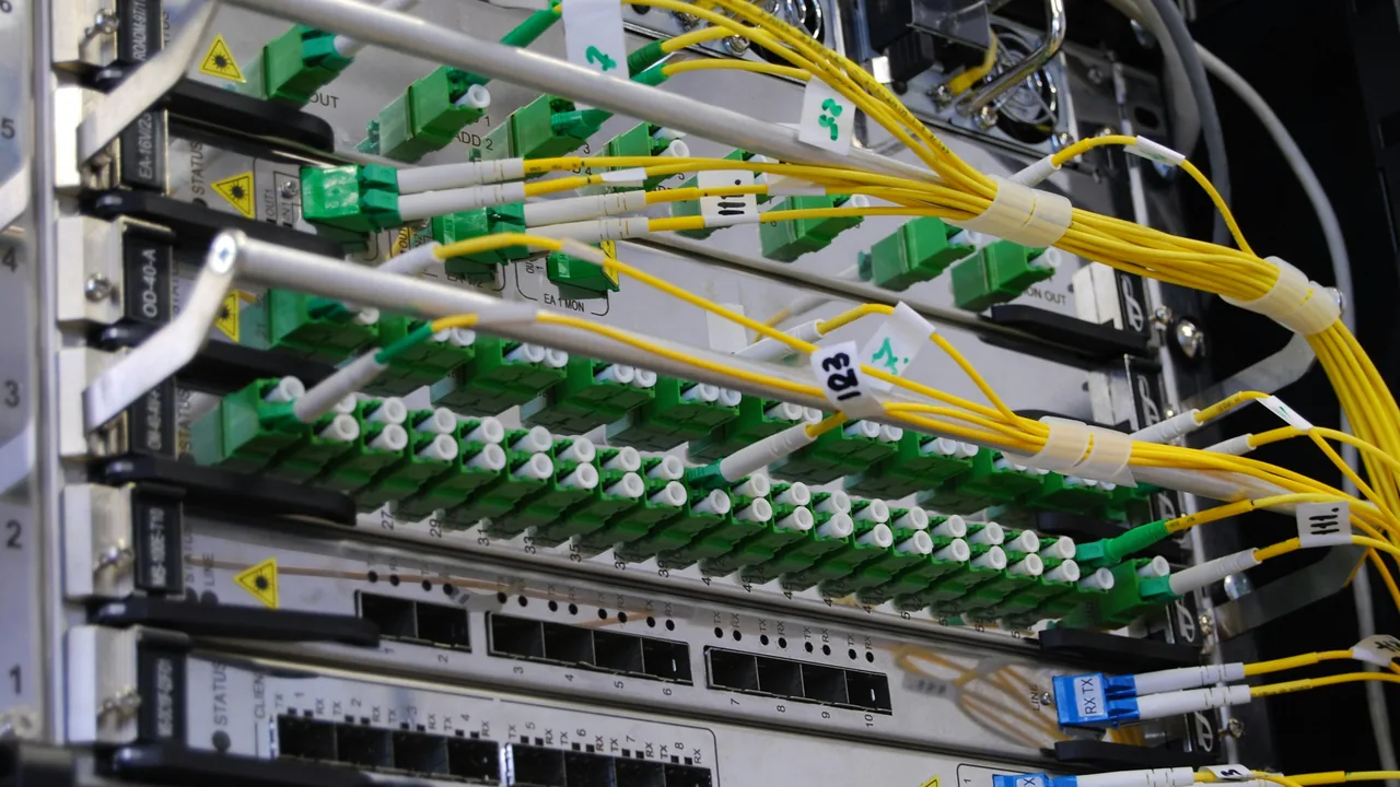Optical panel with a row of numbered green sockets and cages for transceiver modules