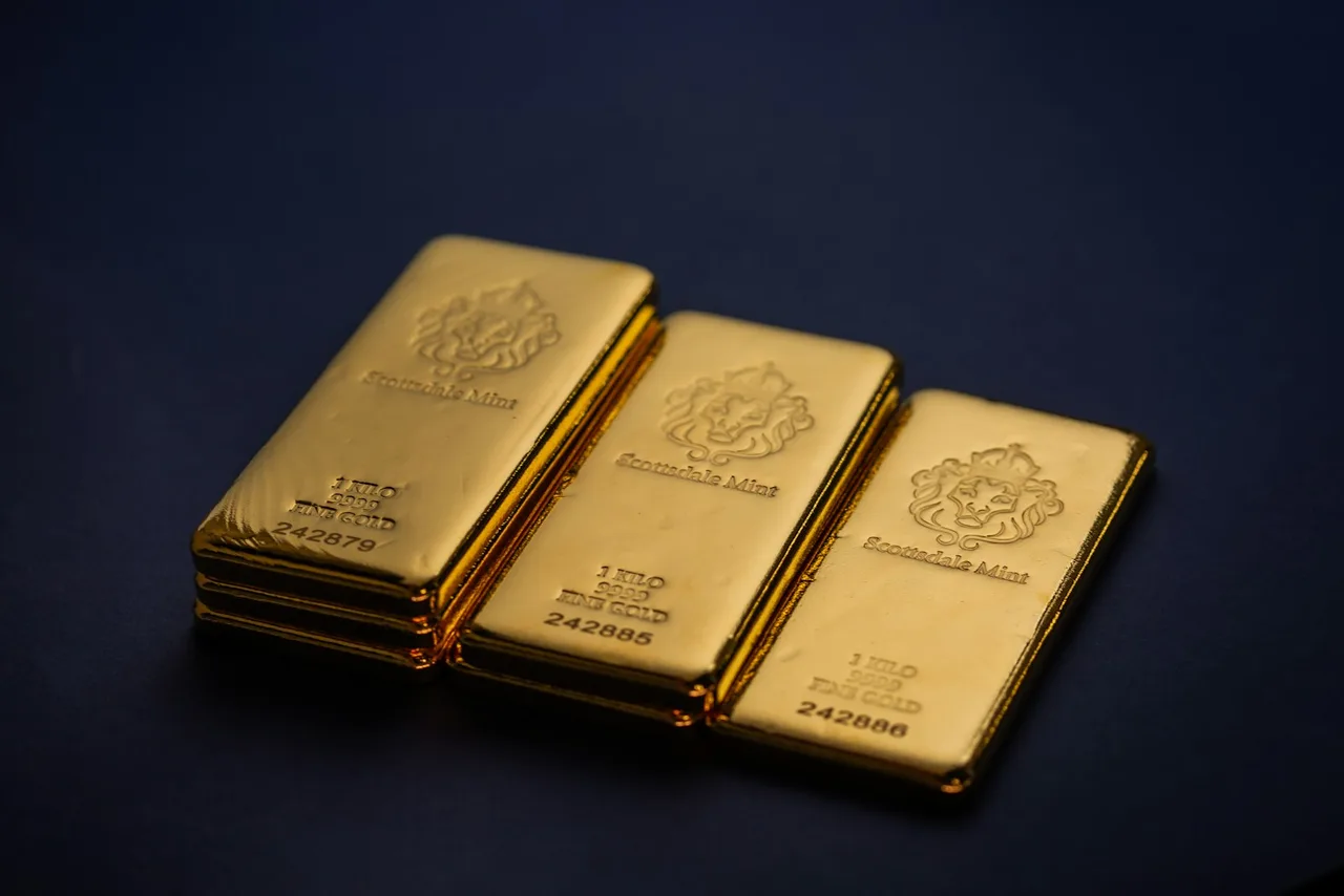 Gold bars laid out in three stacks, stamped 1 KILO 9999 FINE GOLD with serial numbers, on a dark blue background