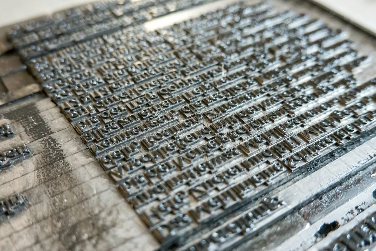 A column of text set line by line in individual pieces of lead type on a printing bed