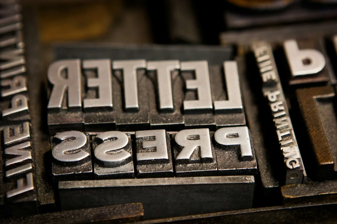 Metal printing type spelling LETTER and PRESS in mirror image, with smaller type reading FINE PRINTING beside it