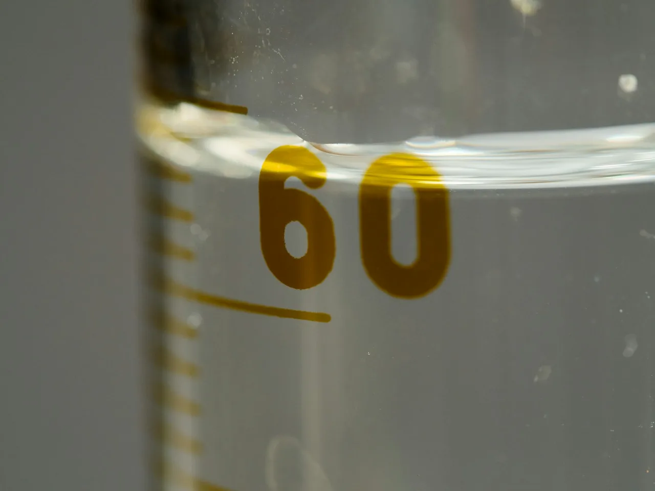 Zbliżenie na cylinder miarowy z liczbą 60 i poziomem cieczy nad tą kreską