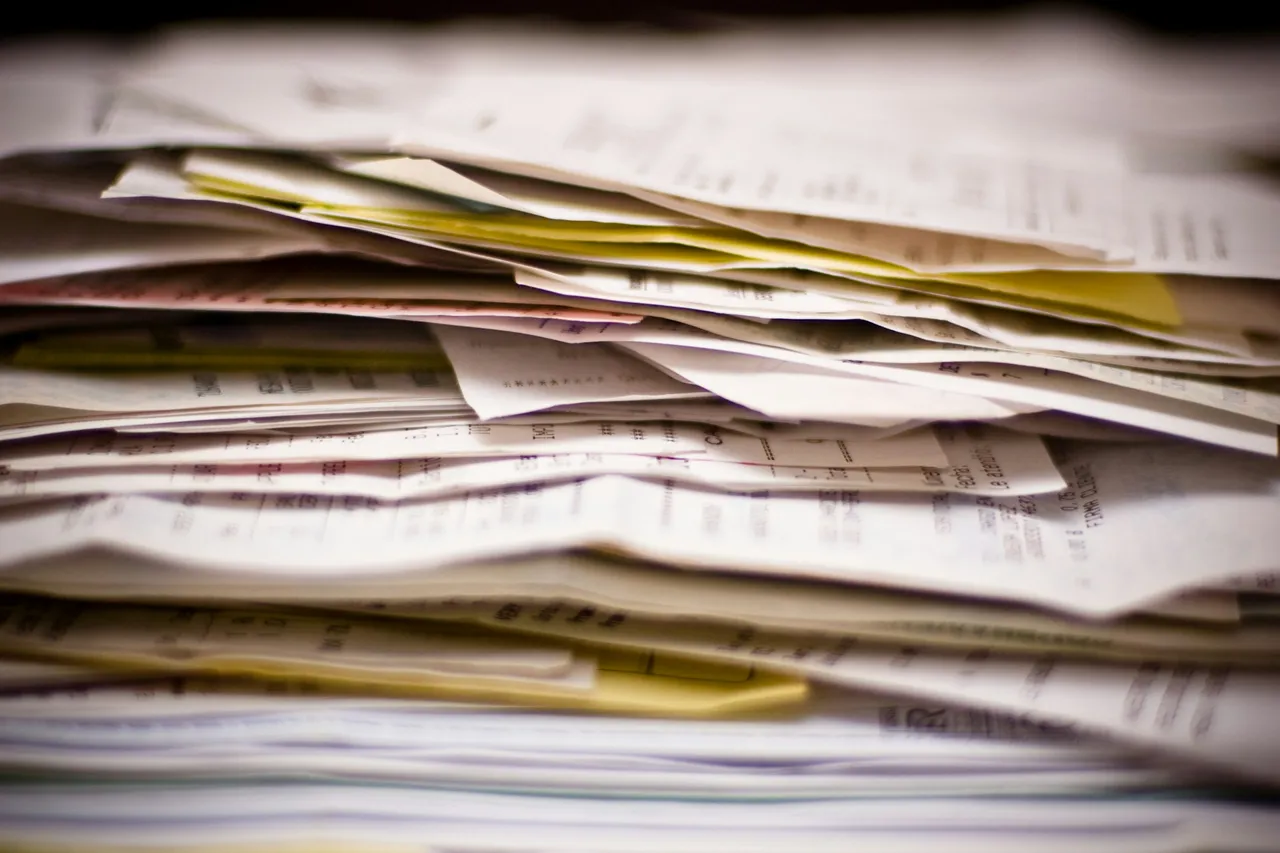 A stack of paper receipts and invoices, some of them yellow